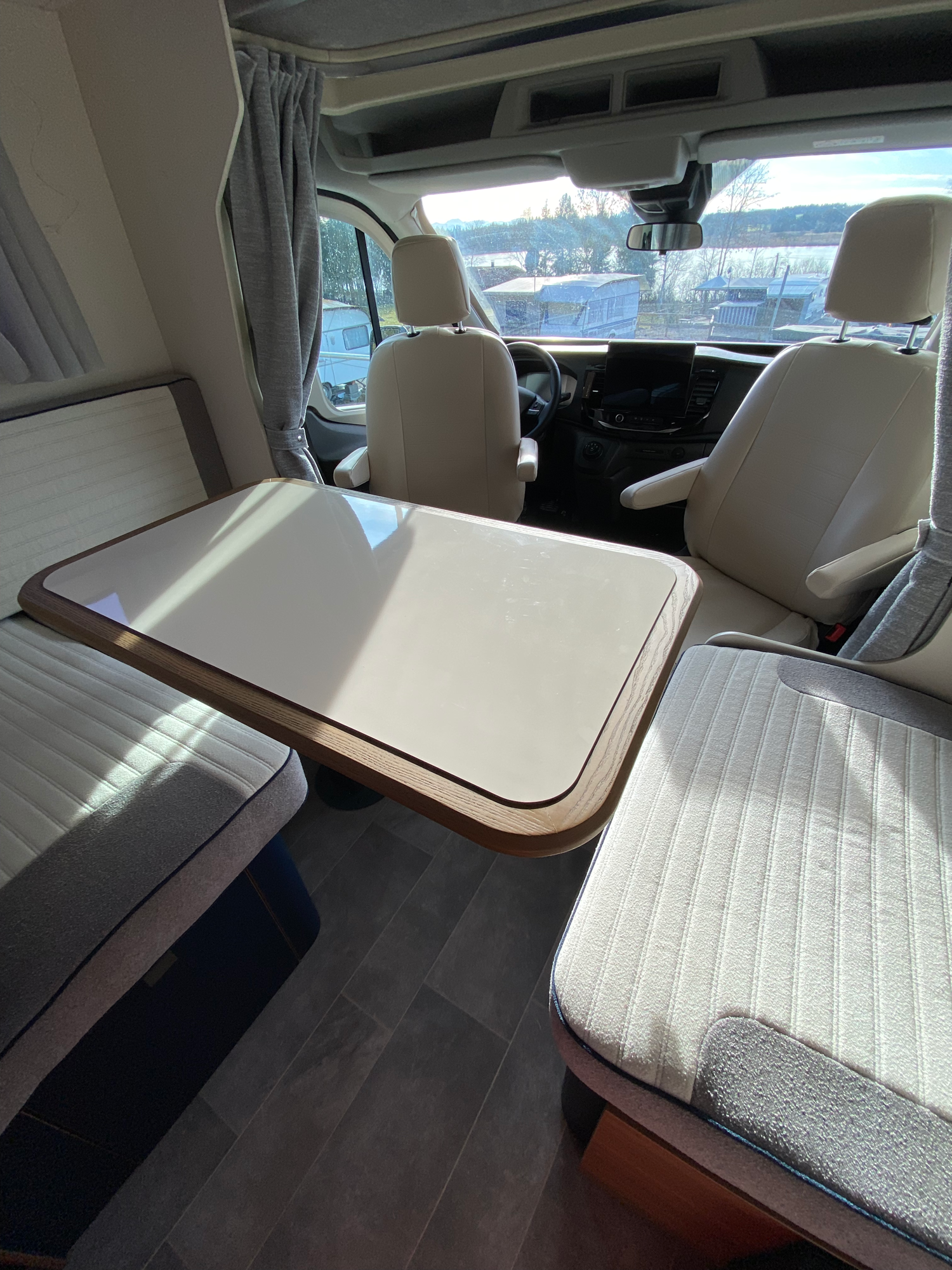 Durch die drehbaren Sessel entstehen bis zu 6 Sitzplätze am Tisch Der Innenraum eines Wohnmobils mit einem Tisch und zwei Sitzen.