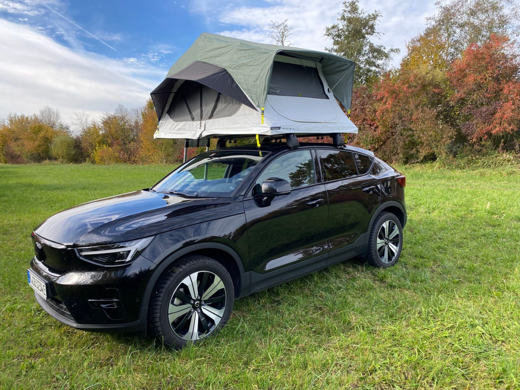Dachzelt MH500 Schwarzes Auto mit aufklappendem Dachzelt auf einer grünen Wiese im Freien.