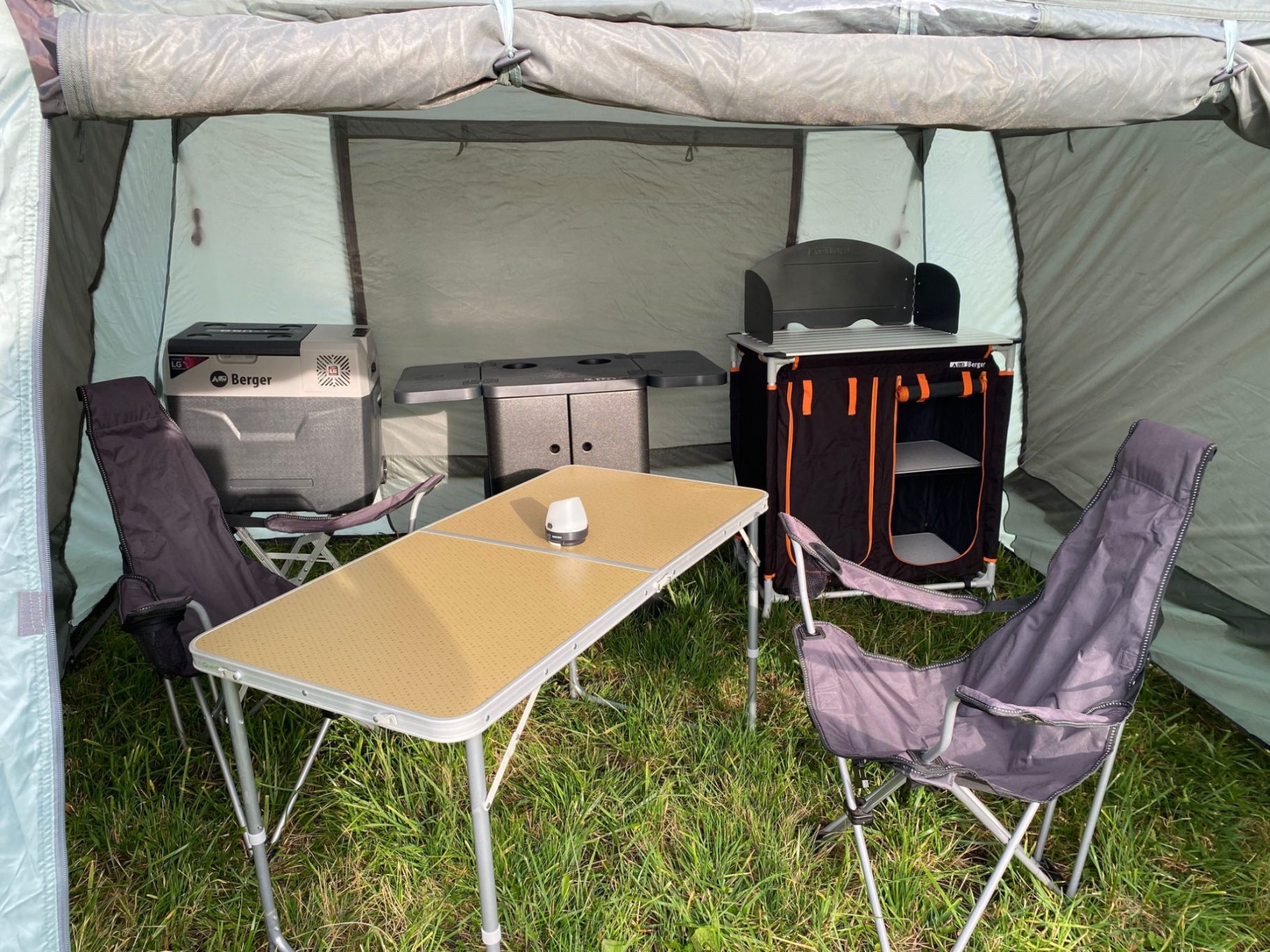 Geräumiges Platzangebot Campingbereich mit Tisch, Stühlen und Kücheneinrichtung in einem Zelt.