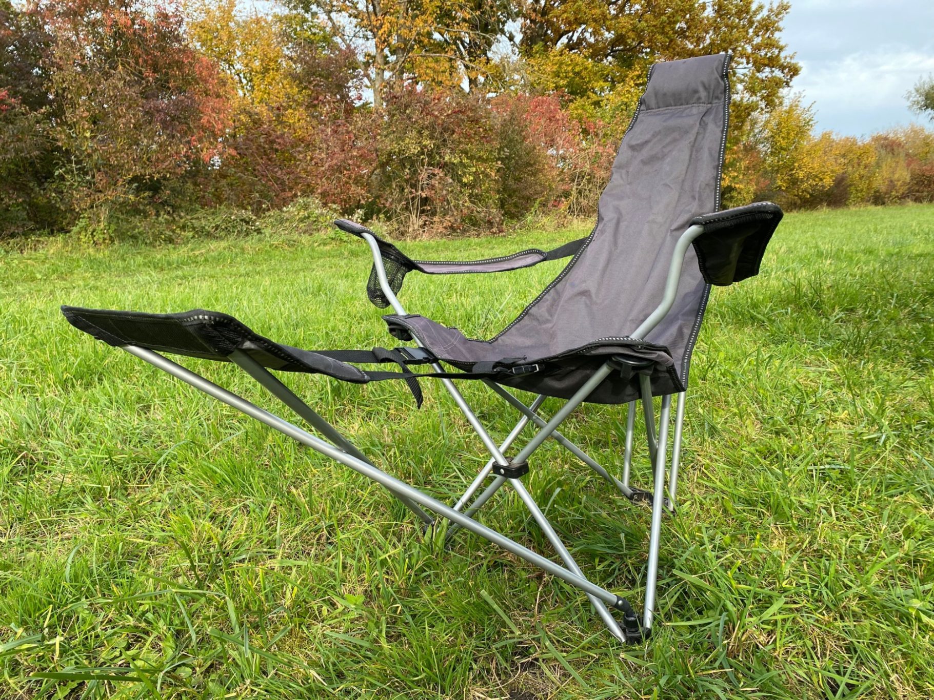 McKinley Klappstuhl mit Fußteil Faltstuhl mit Fußstütze auf einer grünen Wiese, umgeben von Bäumen.