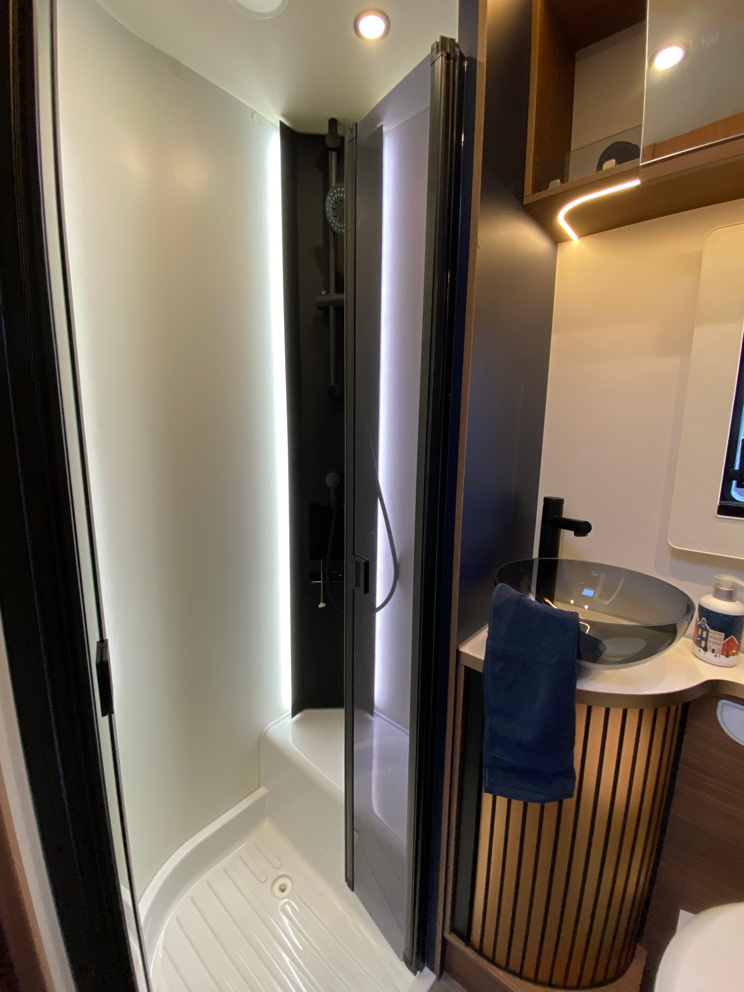 Dusche mit Glastüren Moderne Duschkabine mit LED-Beleuchtung und Waschbecken in einem Badezimmer.