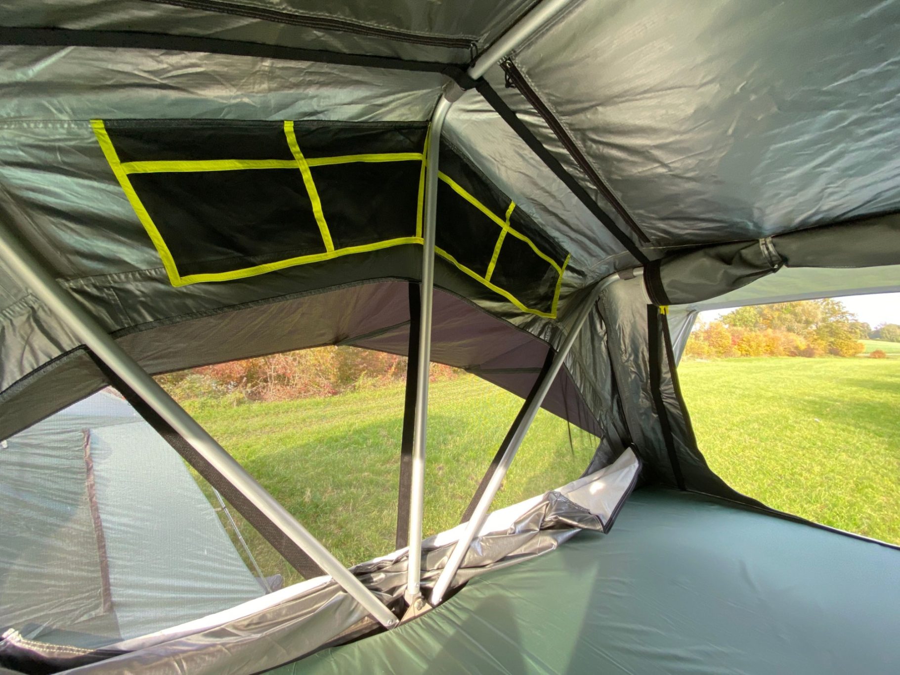 offene Seitenteile Innenansicht eines Zeltes mit Fenstern und grünen Akzenten.