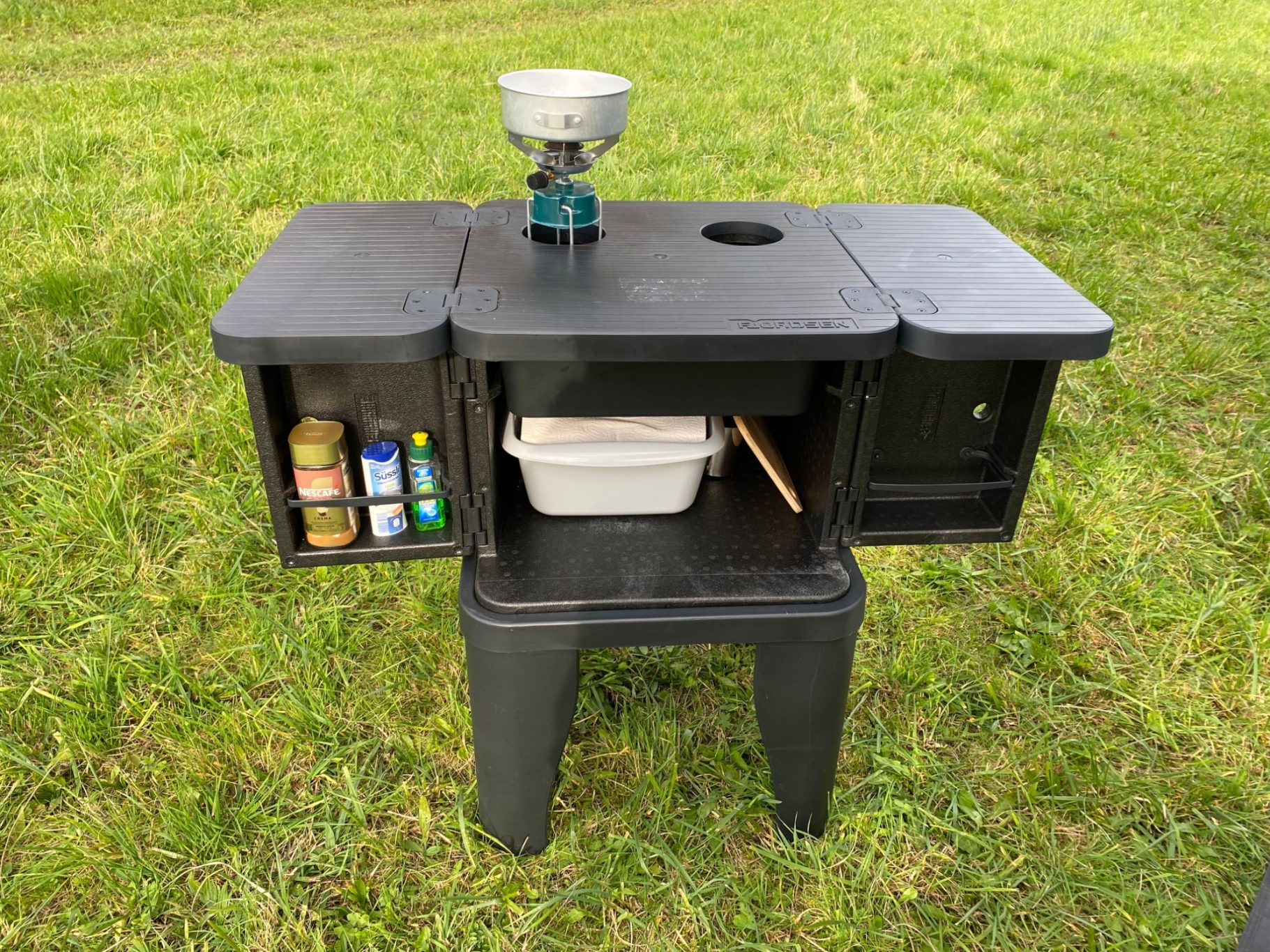 Outdoorküche geöffnet Kompakte Campingküche mit Kochplatte und Stauraum für Lebensmittel und Utensilien.