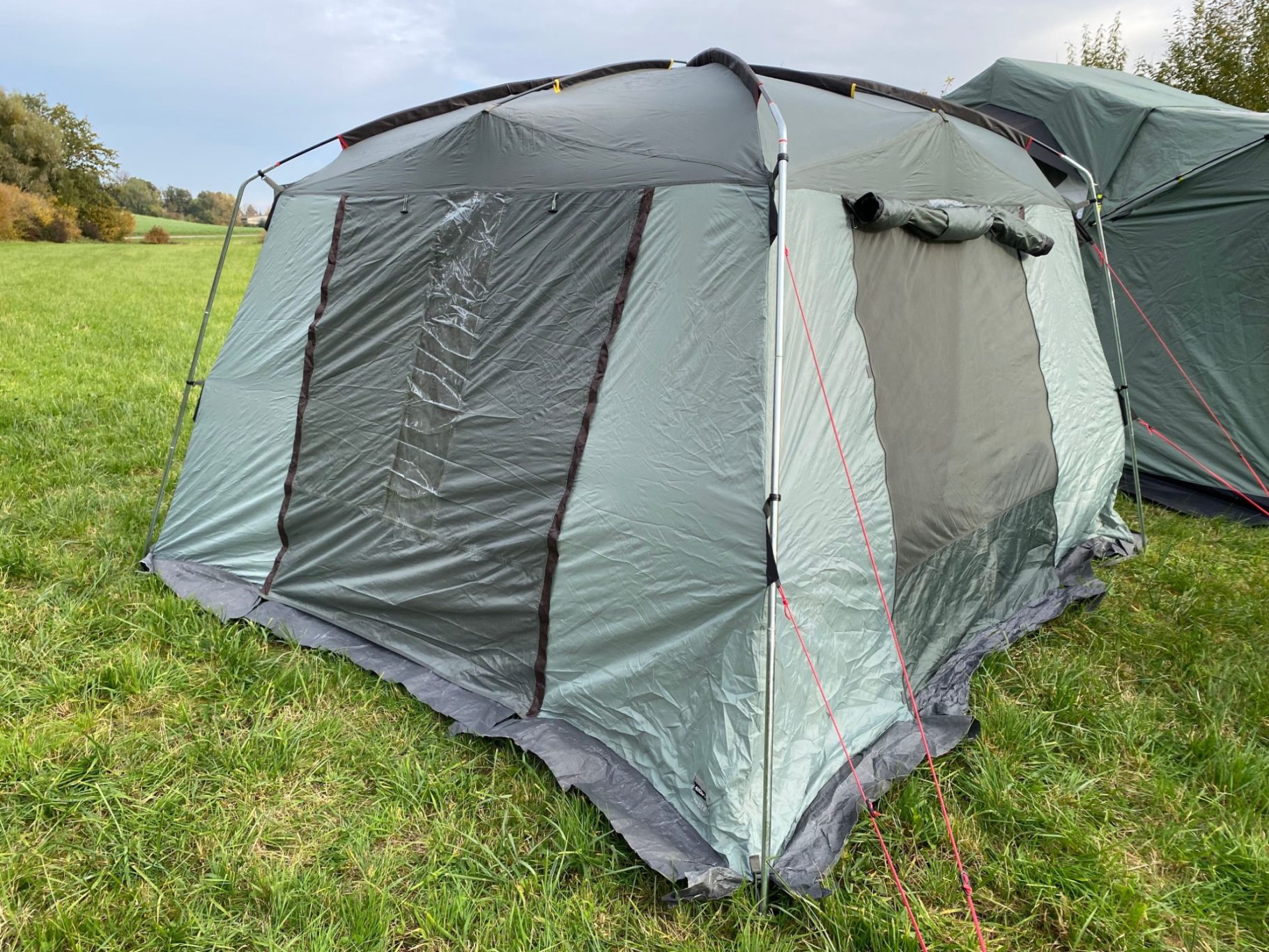 Mückennetze am Eingang Zelt auf einer Wiese, mit gefaltetem Stoff und Zugseilen.