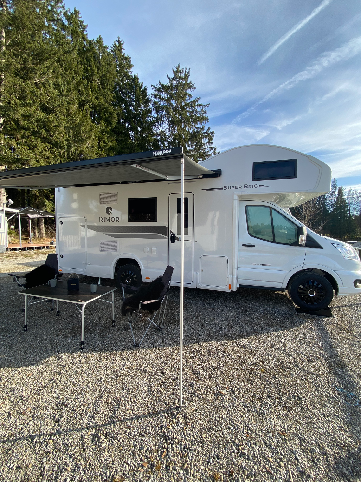 Aussenansicht inkl. der großen Markise Weißer Wohnmobil mit Markise und Außenbereich in einer natürlichen Umgebung.