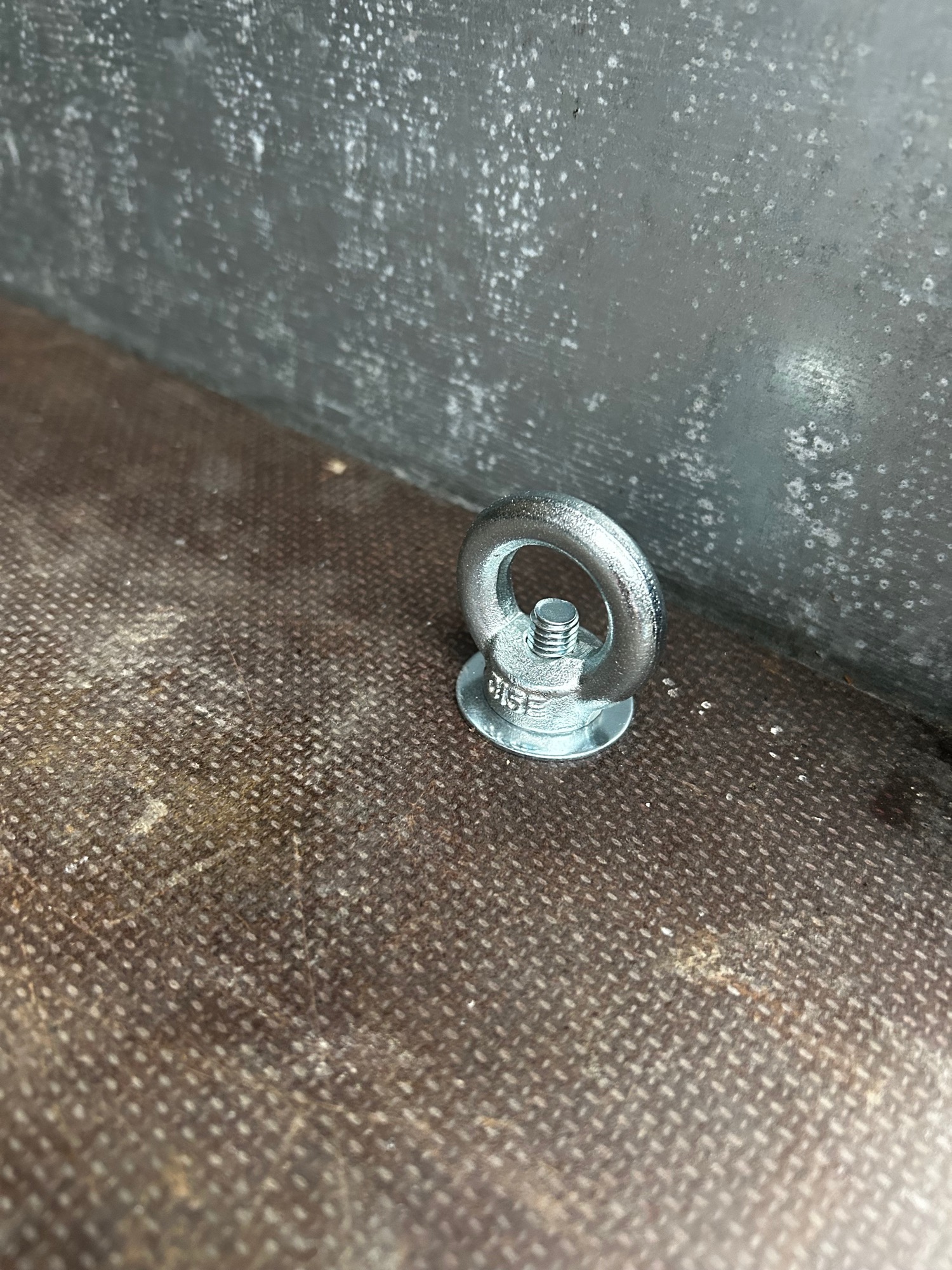 Stabile Zurrösen Metallöse mit Schraube auf einer rauen Oberfläche.