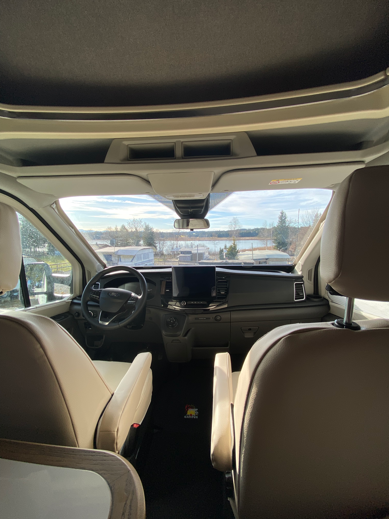 Das große & bequeme Fahrerhaus Blick ins Innere eines Fahrzeugs mit fokussiertem Armaturenbrett und Fenstern.