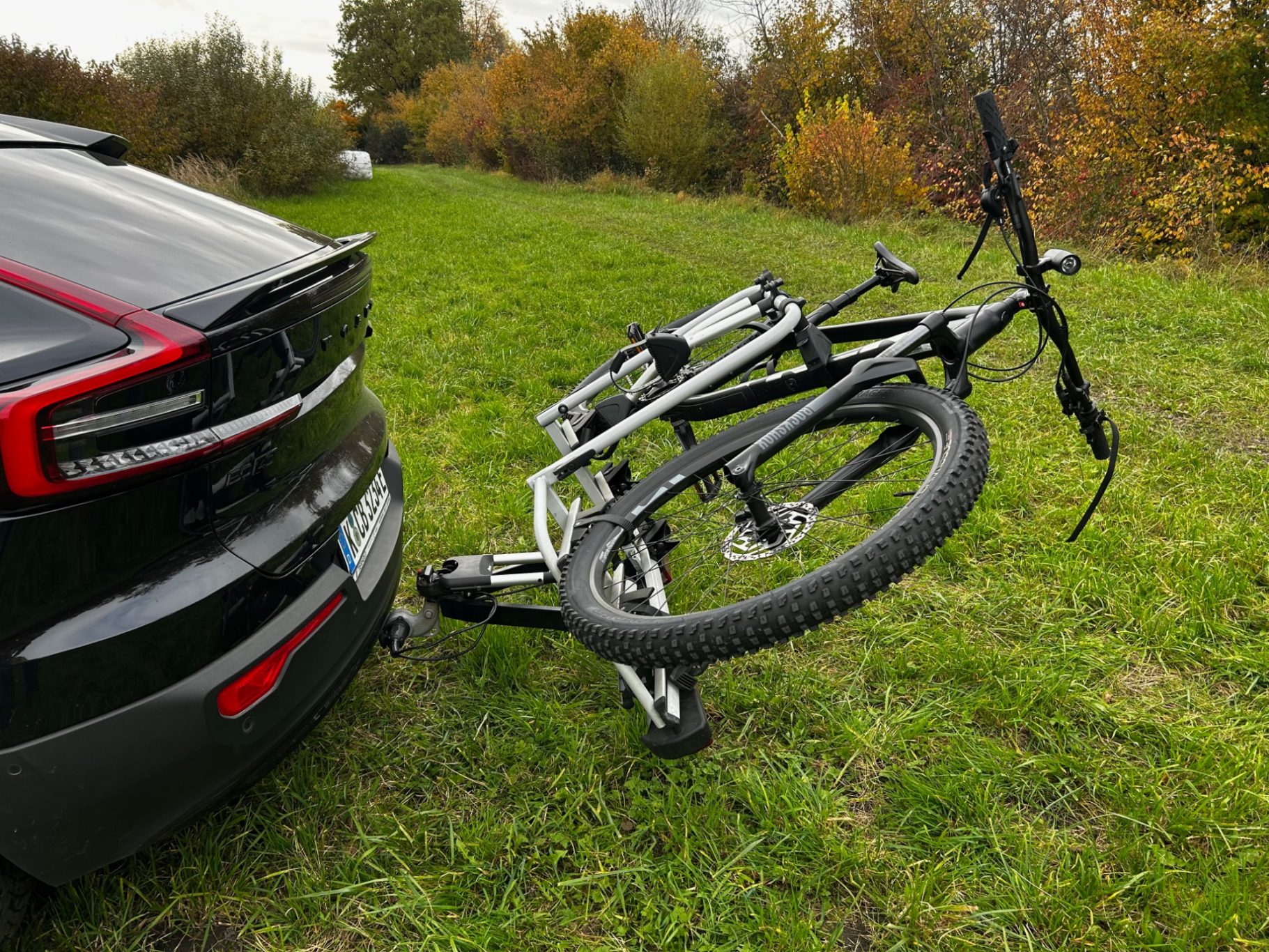 Abgeklappt um den Kofferraum zu öffnen Ein schwarzes Auto mit einem Fahrradträger, auf dem zwei Mountainbikes montiert sind.