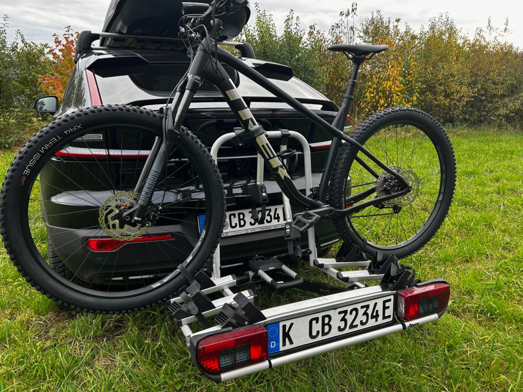 Radlträger Atera Strada Schwarzes Fahrrad auf einem Trägersystem an einem Auto, Parkbereich im Freien.