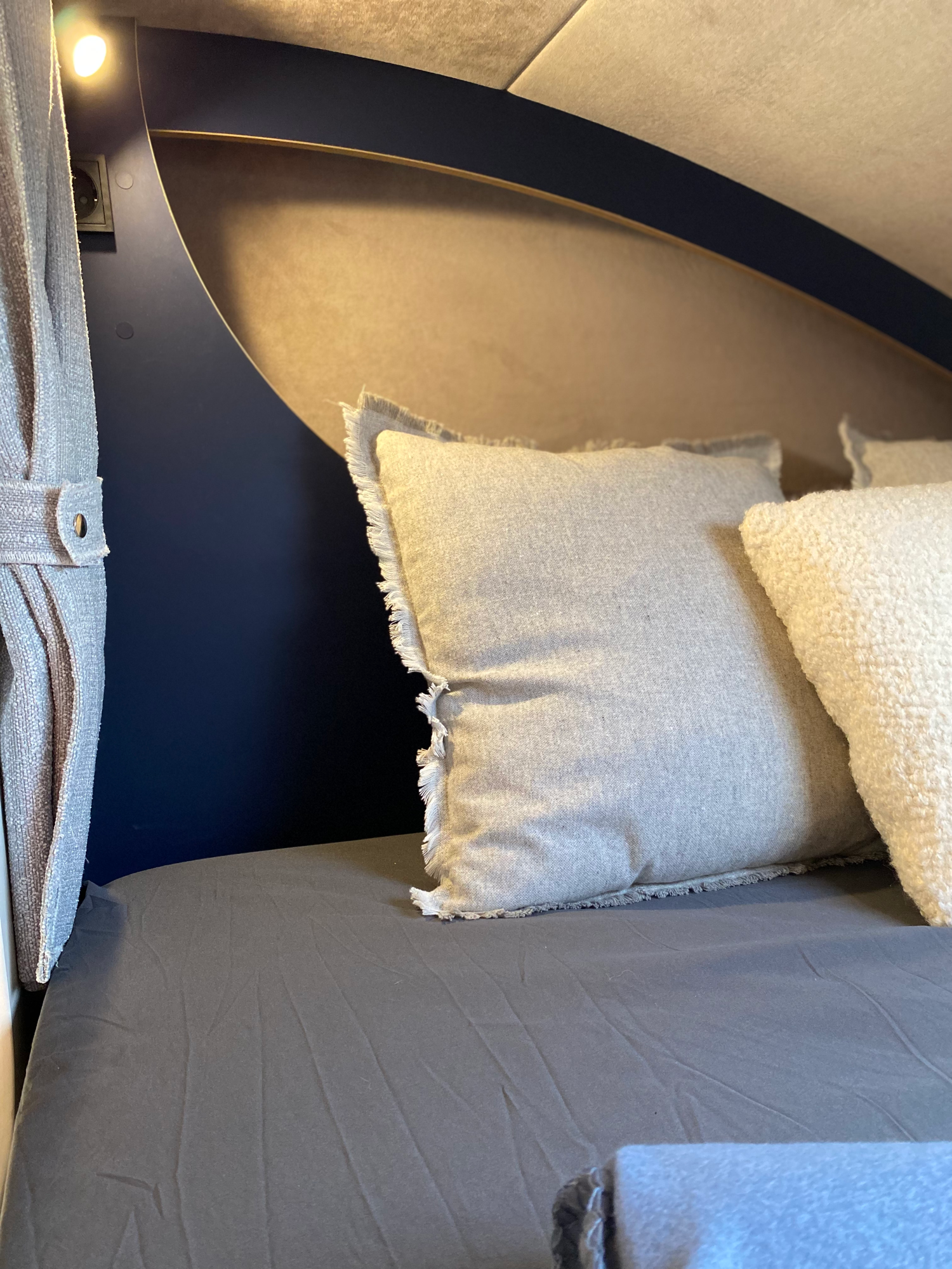 Das große Alkovenbett bietet mit 140x220cm ausreichend Platz Bett mit blauen Akzenten und dekorativen Kissen auf einem neutralen Untergrund.