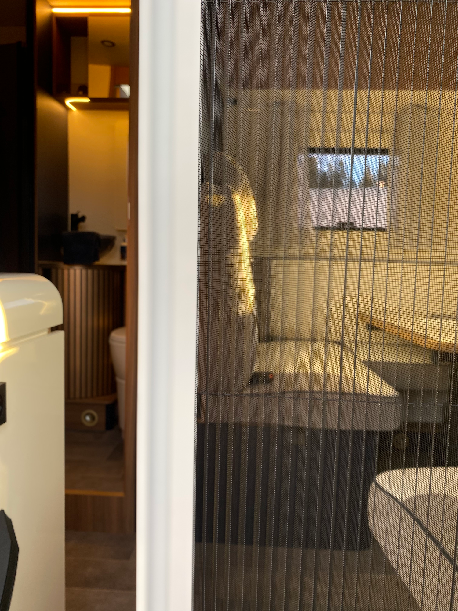 Eingang inkl. der zusätzlichen Insektenschutztür Innenansicht eines modernen Wohnraums mit einem gemütlichen Sitzbereich und einer Küchenzeile.