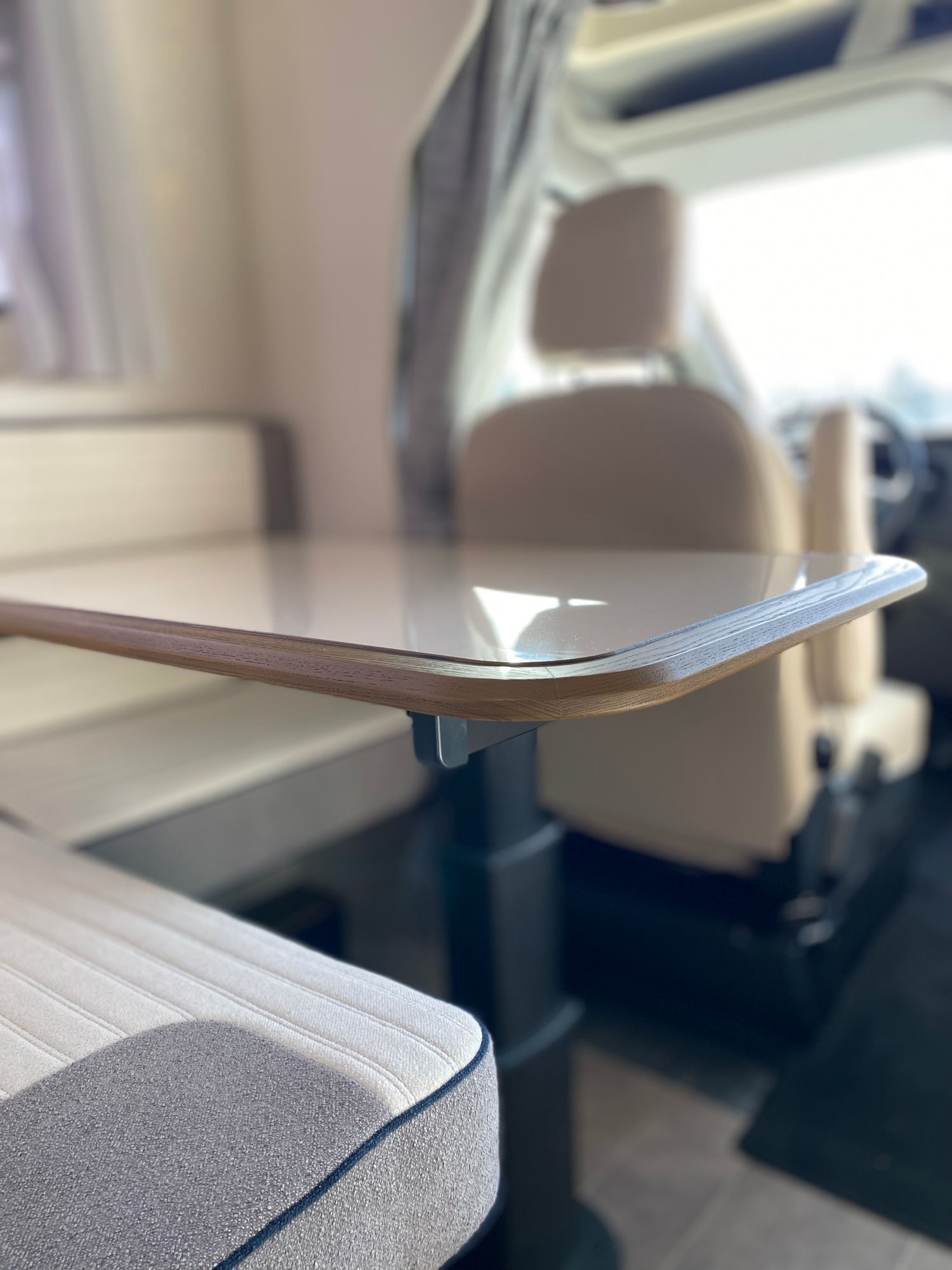 Vielfältig verstellbarer Tisch der Sitzgruppe Tisch in einem Wohnmobil mit gepolsterten Sitzen im Hintergrund.